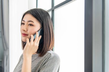 Asyalı çalışan kadın cep telefonuyla konuşuyor. Evde rahatça çalışıyorum. Ofiste çalışıyorum..