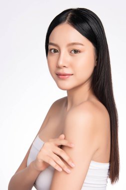 Güzel, genç Asyalı bir kadın vücuduna yeni sağlıklı bir ciltle dokunuyor, beyaz arka planda izole edilmiş, güzellik estetiği ve yüz bakımı konsepti.