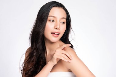 Güzel, genç Asyalı bir kadın vücuduna yeni sağlıklı bir ciltle dokunuyor, beyaz arka planda izole edilmiş, güzellik estetiği ve yüz bakımı konsepti.