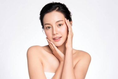 Güzel, genç Asyalı bir kadın temiz yüzüne yeni sağlıklı bir ciltle dokunuyor, beyaz arka planda izole edilmiş, Güzellik Kozmetik ve Yüz Bakımı Konsepti,