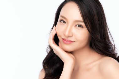 Güzellik Surat 'ı kapatın. Gülümseyen Asyalı kadın sağlıklı deri portresine dokunuyor. Güzel, mutlu bir kız modeli. Taze, nemli bir cildi ve beyaz arka planda doğal makyajı var.,