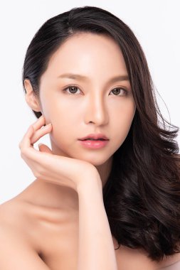 Güzellik Surat 'ı kapatın. Gülümseyen Asyalı kadın sağlıklı deri portresine dokunuyor. Güzel, mutlu bir kız modeli. Taze, nemli bir cildi ve beyaz arka planda doğal makyajı var.,