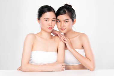 Temiz ciltli iki güzel Asyalı kadın, beyaz arka planda, yüz bakımı, yüz bakımı. Kozmetik, güzellik ve kaplıca. Asyalı kadın portresi