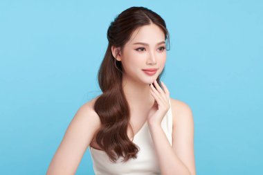 Güzel, genç bir Asyalı kadın, temiz, taze bir cilde sahip, mavi bir arka planda. Cilt bakımı, yüz bakımı, kozmetoloji, güzellik ve kaplıca. Asyalı bir kadının zarif bir portresi..