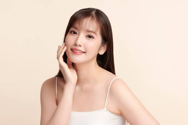 Güzel, genç bir Asyalı kadın, bej bir arka planda temiz, taze bir ten. Cilt bakımı, yüz bakımı, kozmetoloji, güzellik ve kaplıca. Asyalı bir kadının zarif bir portresi..