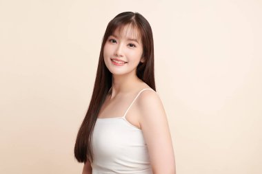 Güzel, genç bir Asyalı kadın, bej bir arka planda temiz, taze bir ten. Cilt bakımı, yüz bakımı, kozmetoloji, güzellik ve kaplıca. Asyalı bir kadının zarif bir portresi..