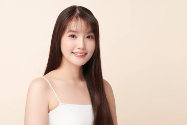 Güzel, genç bir Asyalı kadın, bej bir arka planda temiz, taze bir ten. Cilt bakımı, yüz bakımı, kozmetoloji, güzellik ve kaplıca. Asyalı bir kadının zarif bir portresi..