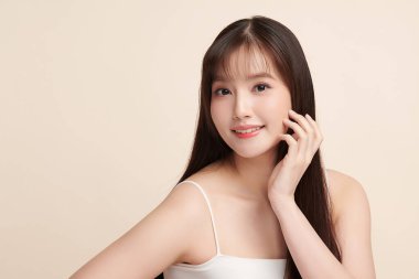 Güzel, genç bir Asyalı kadın, bej bir arka planda temiz, taze bir ten. Cilt bakımı, yüz bakımı, kozmetoloji, güzellik ve kaplıca. Asyalı bir kadının zarif bir portresi..