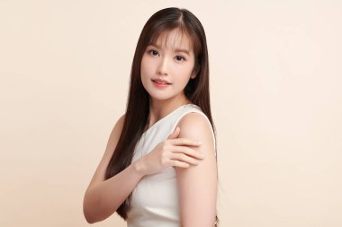 Güzel, genç bir Asyalı kadın, bej bir arka planda temiz, taze bir ten. Cilt bakımı, yüz bakımı, kozmetoloji, güzellik ve kaplıca. Asyalı bir kadının zarif bir portresi..