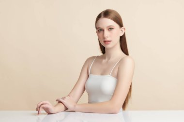 Güzel, genç bir Asyalı kadın, bej bir arka planda temiz, taze bir ten. Cilt bakımı, yüz bakımı, kozmetoloji, güzellik ve kaplıca. Asyalı bir kadının zarif bir portresi..