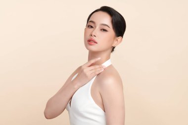 Güzel, genç bir Asyalı kadın, bej bir arka planda temiz, taze bir ten. Cilt bakımı, yüz bakımı, kozmetoloji, güzellik ve kaplıca. Asyalı bir kadının zarif bir portresi..