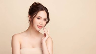 Güzel, genç bir Asyalı kadın, bej bir arka planda temiz, taze bir ten. Cilt bakımı, yüz bakımı, kozmetoloji, güzellik ve kaplıca. Asyalı bir kadının zarif bir portresi..