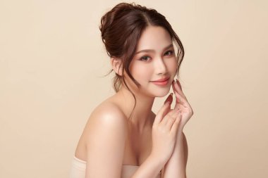 Güzel, genç bir Asyalı kadın, bej bir arka planda temiz, taze bir ten. Cilt bakımı, yüz bakımı, kozmetoloji, güzellik ve kaplıca. Asyalı bir kadının zarif bir portresi..