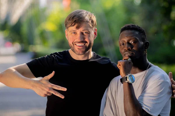 Black guy and white guy hug and stare. Interracial friendship