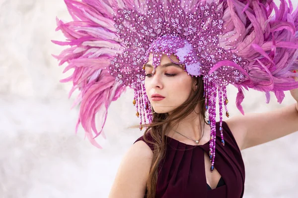 A girl with a large purple feather crown. Brazillian carnival