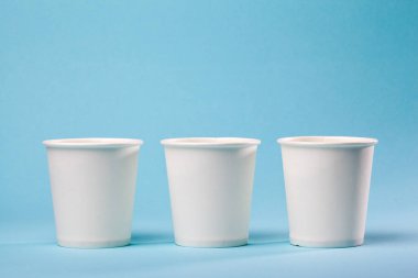 Üç boş kağıt bardak su, kahve, çay veya mavi bir arka plan üzerinde diğer sıcak ve soğuk içecekler için.