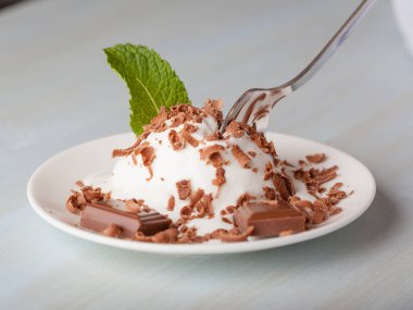 Nane ve bir kaşık ve hafif bir arka plan üzerine bir fincan tabağı çikolata ile dondurma