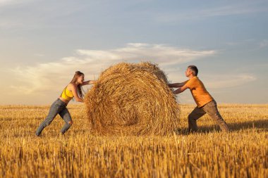 Erkek ve kadın birbirlerine doğru bir saman balya bastırıyor. Birlik ve karşıtların mücadele diyalektik prensibi kavramı