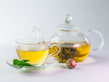 Şeffaf cam Çaydanlık ve bardak çiçek çay ve kuru çay çiçek topu hafif bir arka plan üzerinde