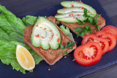 Dilimlenmiş avokado tost ve domates koyu arka plan üzerinde yakın çekim