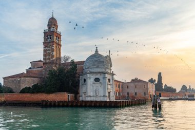 Venice, İtalya - 28 Aralık 2018: Venedik Lagoon görünümüne Isola günbatımı gökyüzünde kuşlar sürüsü ile San Michele