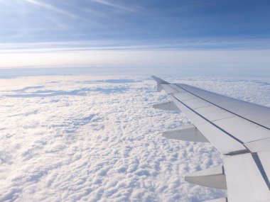 Kanat ve dünyayı kaplayan bulutlar sonsuz expanses için dar bir uçak penceresinden görüntülemek