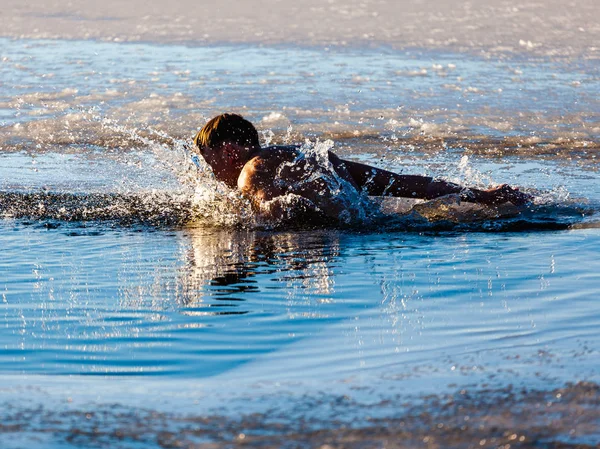 A man swimming in ice water close-up