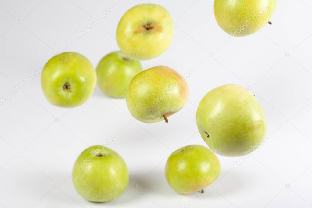 Flying whole green apples on light background. Closeup
