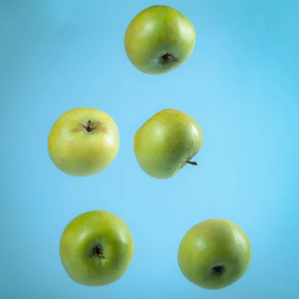 Mavi bir arka plan, uçan yeşil elma. Portre