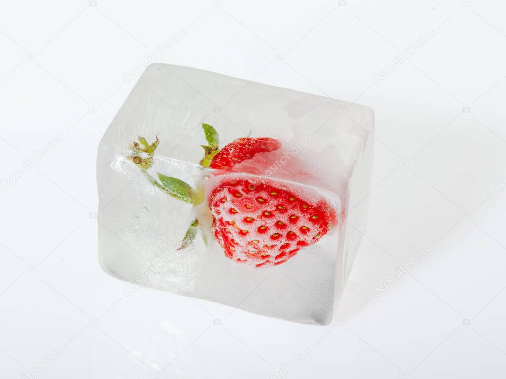 Fresh red strawberrie frozen in the ice on white background closeup. Concept of freezing fruits.