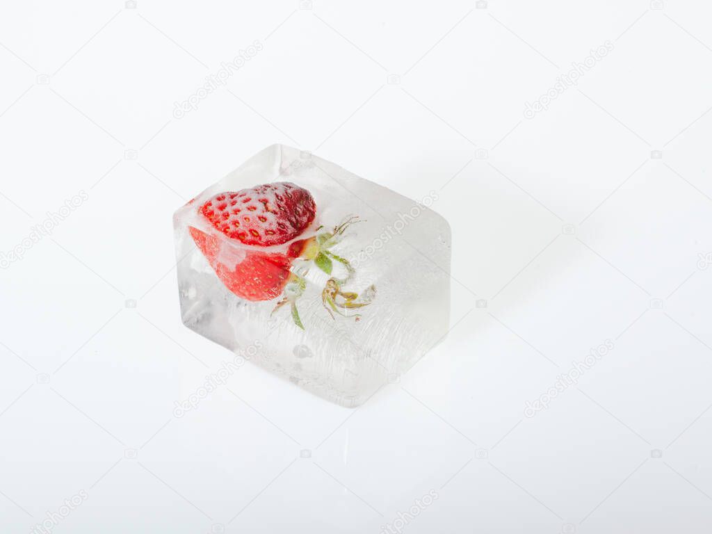 Strawberry frozen in the ice on white background closeup. Concept of freezing fruits.