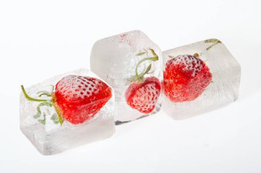 Beyaz arkaplanda buzun içinde donmuş çilek. Dondurulmuş meyve kavramı