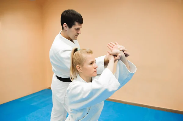 Man and woman fighting at Aikido training in martial arts school.