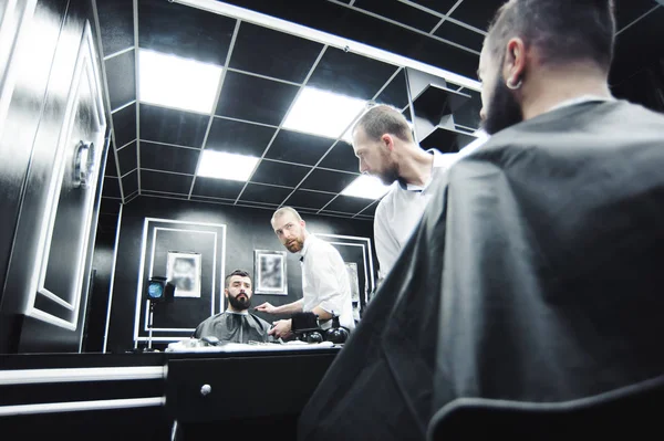Master cuts hair and beard of men in the barbershop, hairdresser