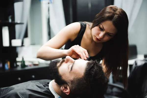 Master cuts hair and beard of men in the barbershop, hairdresser