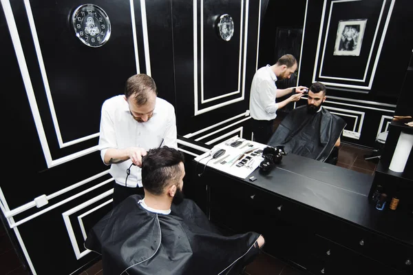 Master cuts hair and beard of men in the barbershop, hairdresser