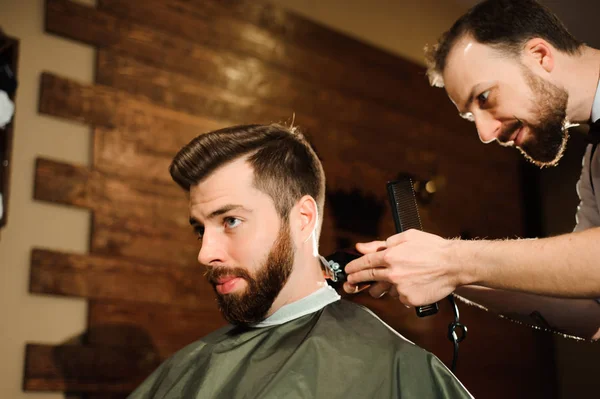 Master cuts hair and beard of men in the barbershop