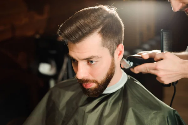 Master cuts hair and beard of men in the barbershop