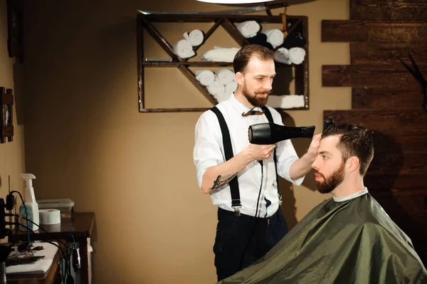 Master cuts hair and beard of men in the barbershop