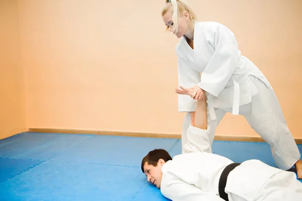 Man and woman fighting at Aikido training in martial arts school