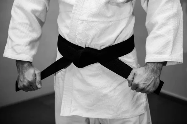 Aikido black belt on white kimono in a sport jum