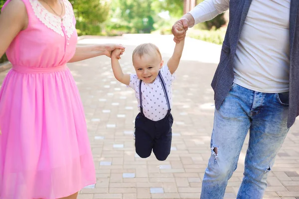 family, parenthood, adoption and people concept - happy mother, father and little boy walking in summer park.