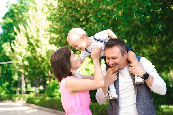 Family, parenthood, adoption and people concept - happy mother, father and little boy walking in summer park.