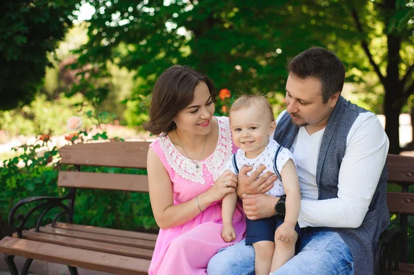 family, parenthood, adoption and people concept - happy mother, father and little boy walking in summer park.