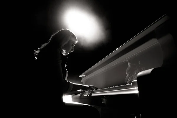 Close up view of a girl plays piano in the concert hall at the scene
