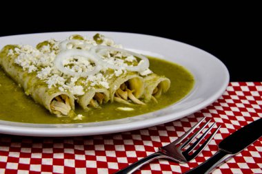 Mexican enchiladas with green sauce cheese and sour cream clipart