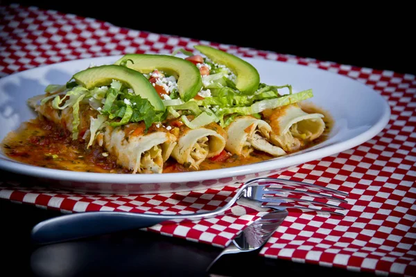 Avokado dilimleri ve parçalanmış peynirli kırmızı Enchilada.