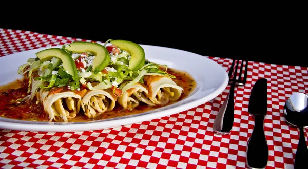 Avokado dilimleri ve parçalanmış peynirli kırmızı Enchilada.