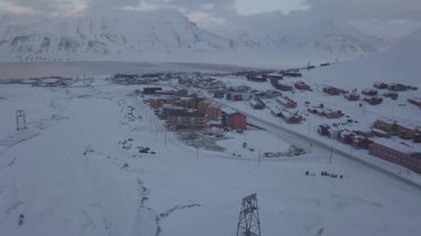 İHA uçuşu. Longyear 'ın havadan görünüşü, Svalbard' ın kışın. Dağlarla ve renkli evlerle manzara. Renk düzeltmesi olmadan D günlüğünde resim. Yüksek kalite 4k görüntü