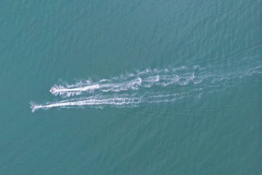 Mavi denize yelken açan sürat teknesinin üst görüntüsü.